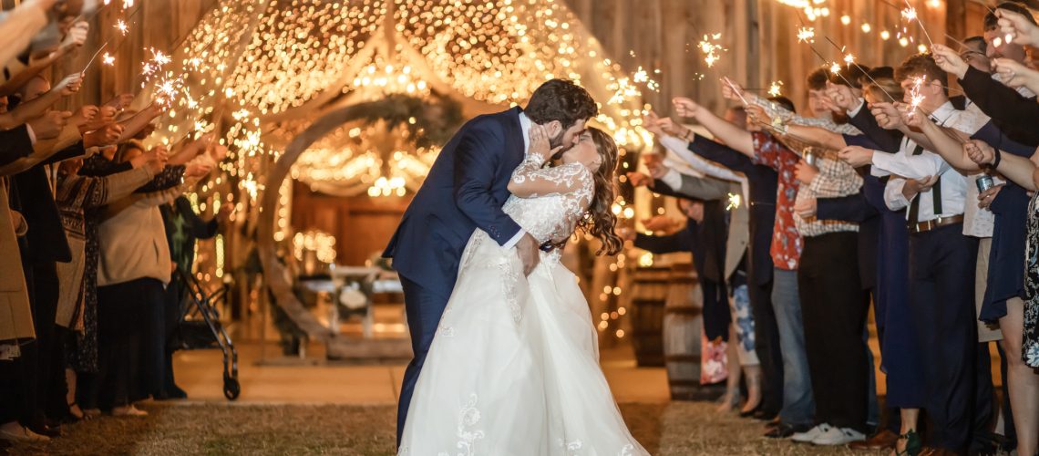 bride and grooms sparkler exit outside of a barn at night